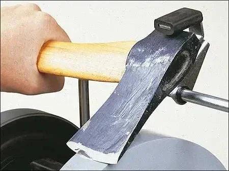 Sharpening an axe blade with a grinding wheel for precision edge restoration.