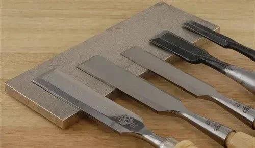 Sharpened chisels on whetstone, ready for precision woodworking tasks