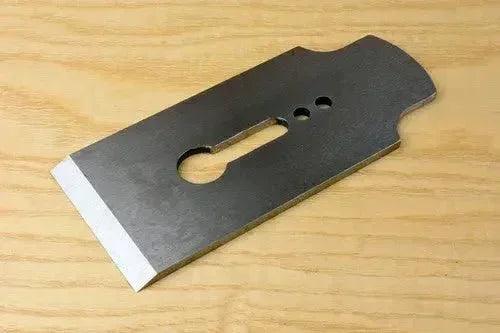 Sharpened plane blade on wooden surface, ready for precision woodworking tasks.