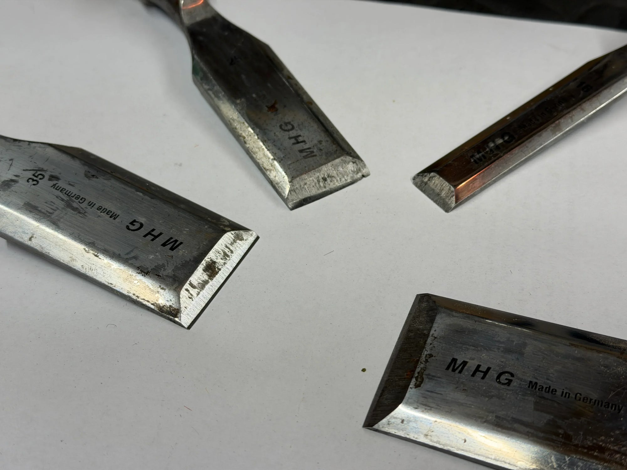 Set of metal tools with 'MHG' branding on a white surface