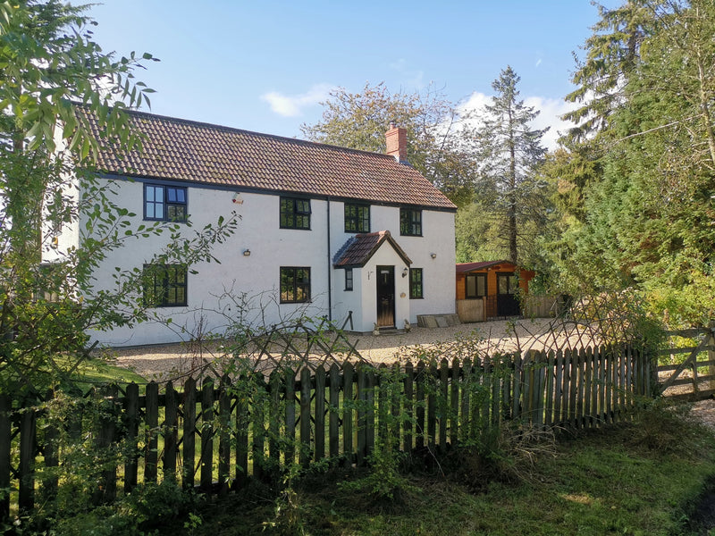 White cottage picture from Touches Lane Chard Small wood fence around it with Rose plant growing up it