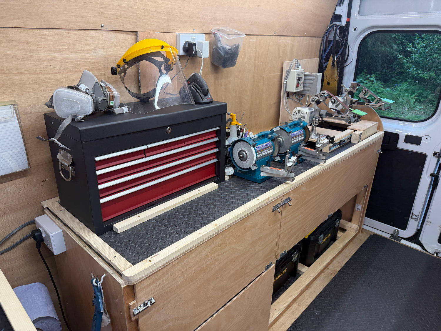Wooden workbench with tools and equipment inside a vehicle