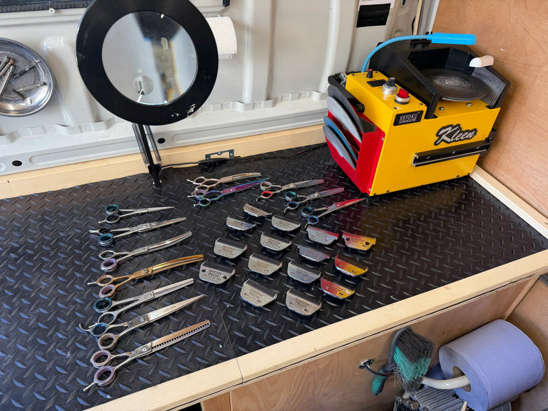 Collection of tools including scissors and clippers on a workbench with a Klean machine.