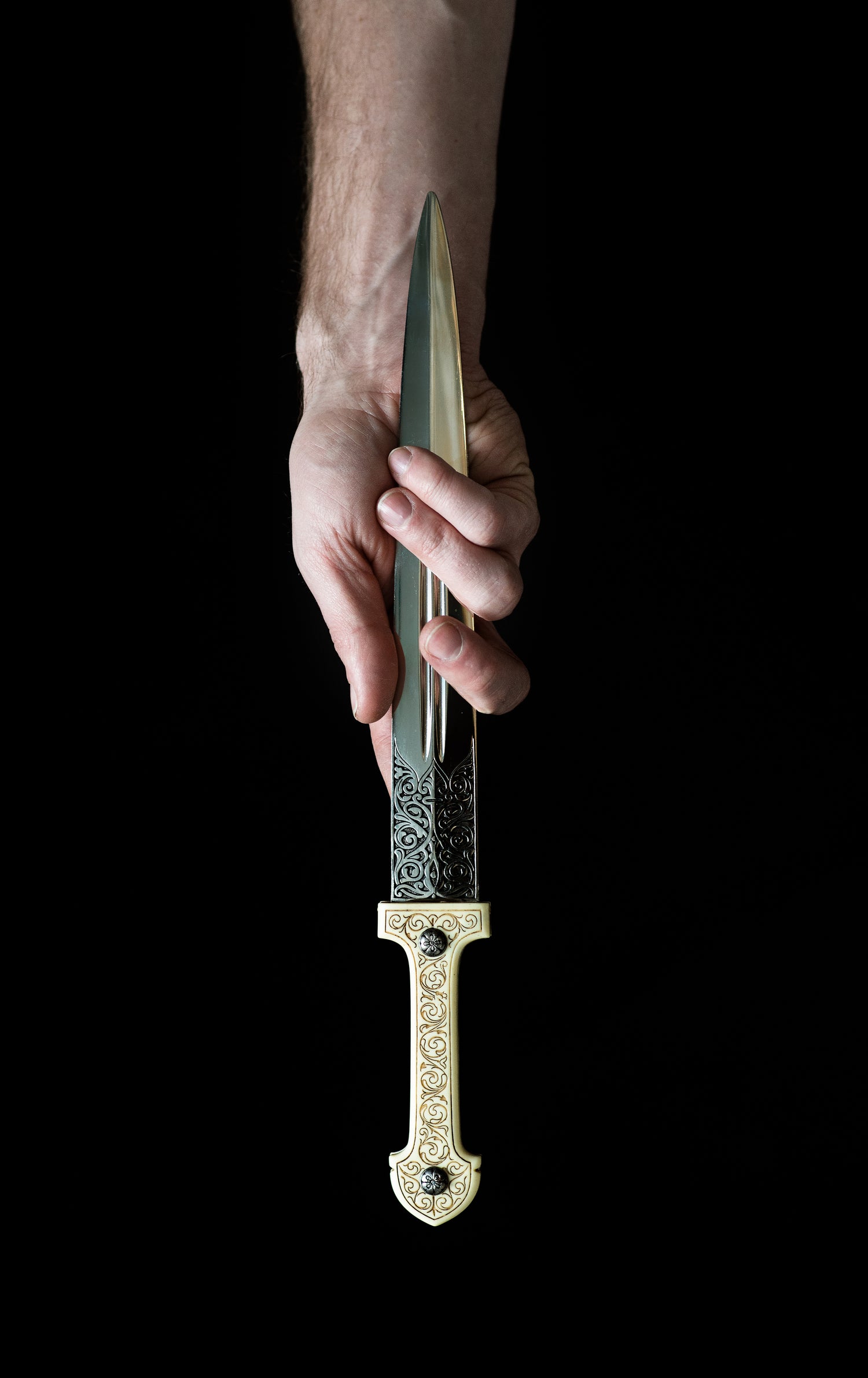 Knife Held in a hand by its blade with black background