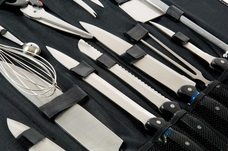 Chef’s knife roll with assorted kitchen knives and tools neatly organised for professional sharpening services.