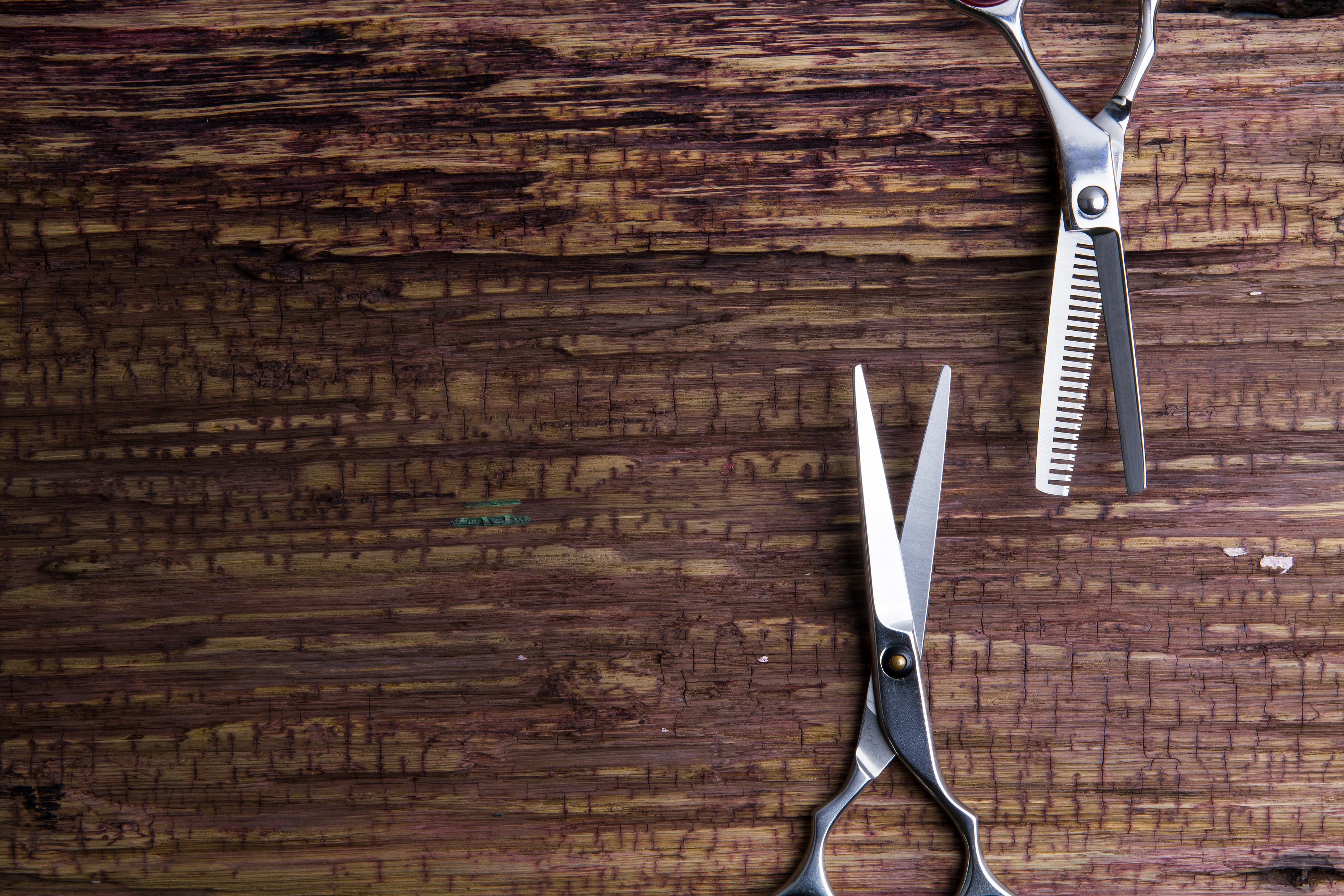 Two pairs of scissors on a wooden surface