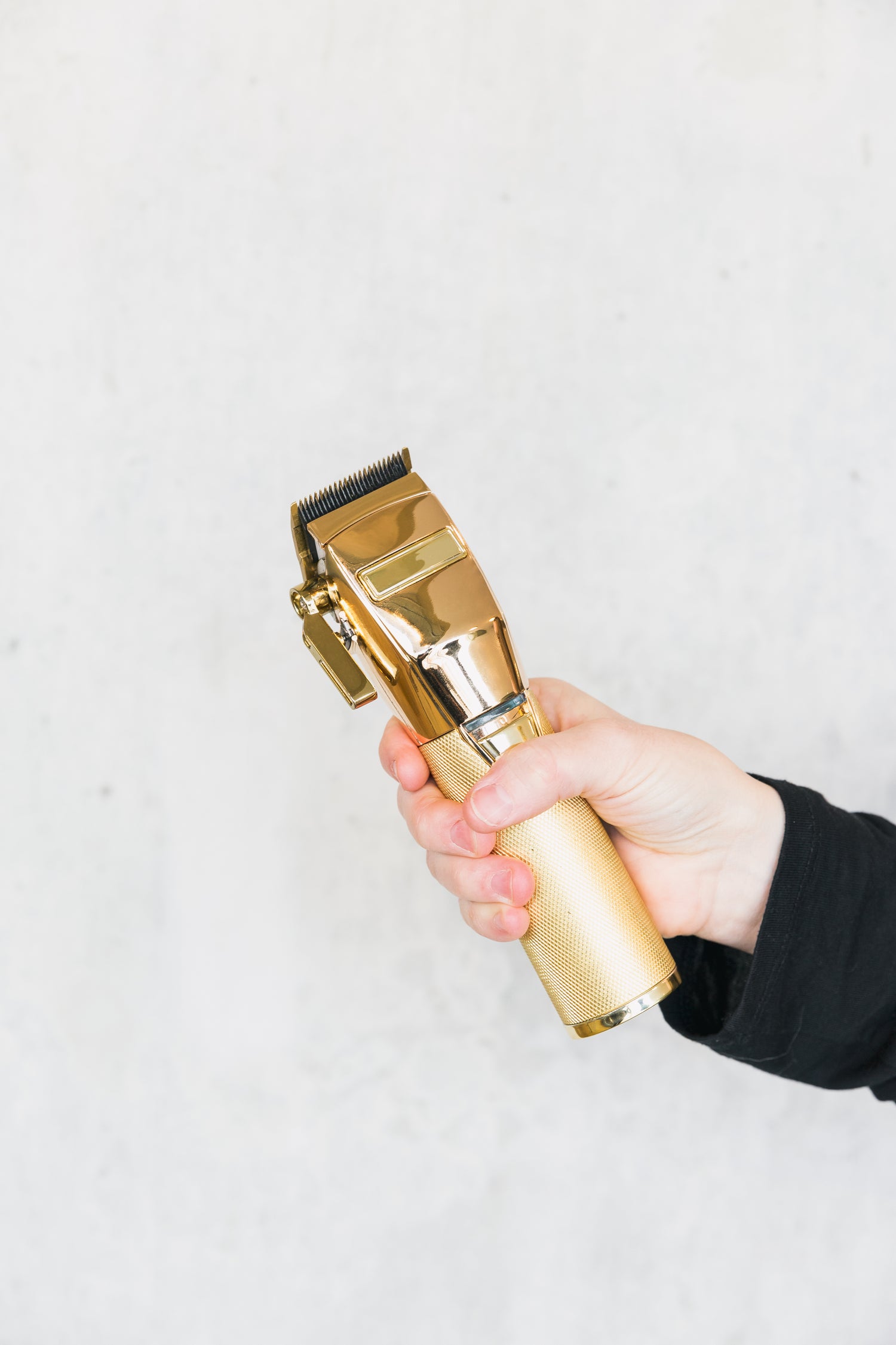 Hand holding a gold clipper with white background
